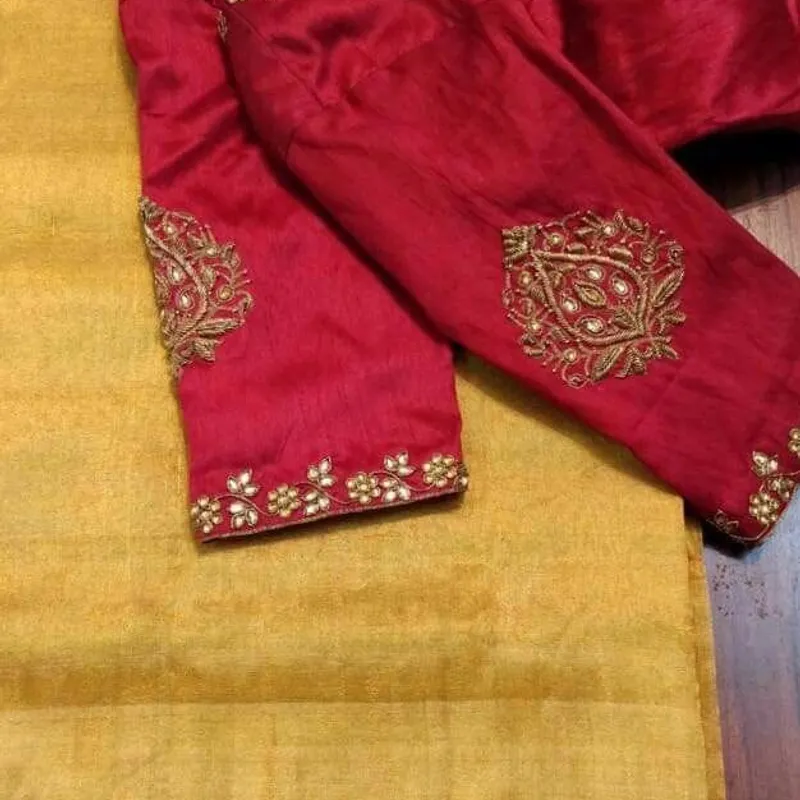 Maroon blouse with gold embroidery motifs on sleeves, paired with gold saree