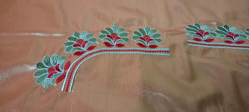 Close-up of leaf embroidery detail on peach fabric